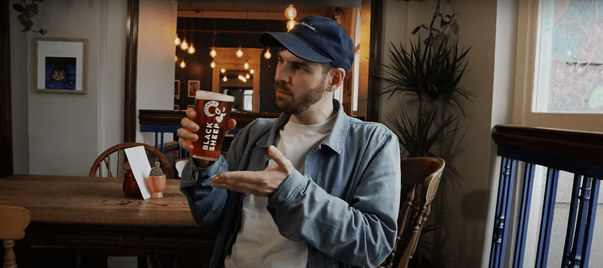 Man holding a pint on beer sat down in a pub