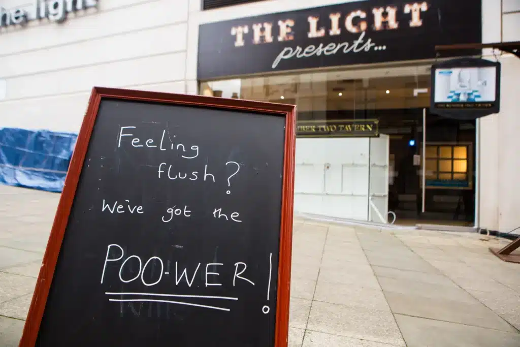 Chalkboard outside the poo-powered pub reading Feeling flush? We've got the poo-wer!