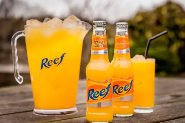 Reef orange and passionfruit bottles with a jug of Reef on ice