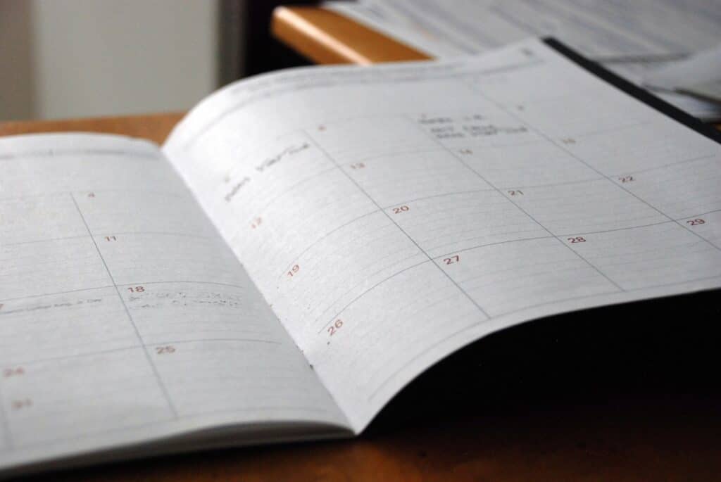 An open monthly planner on a wooden desk used to plan a food product launch timeline