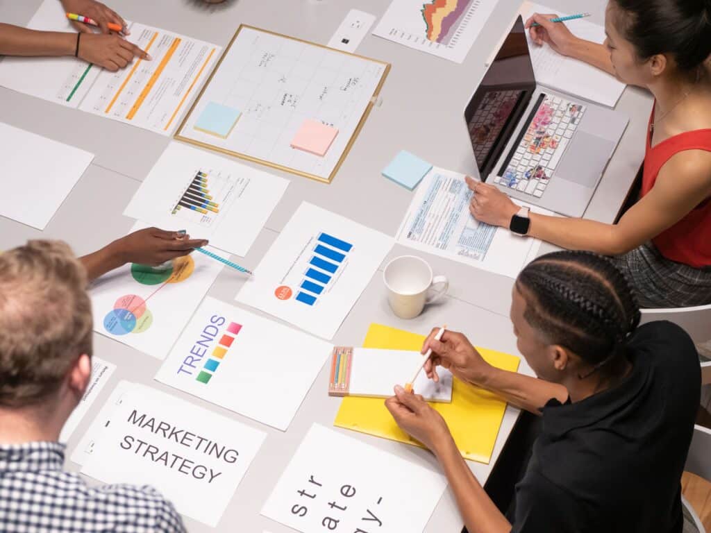 PR team planning a product launch around a table with marketing strategy documents and charts