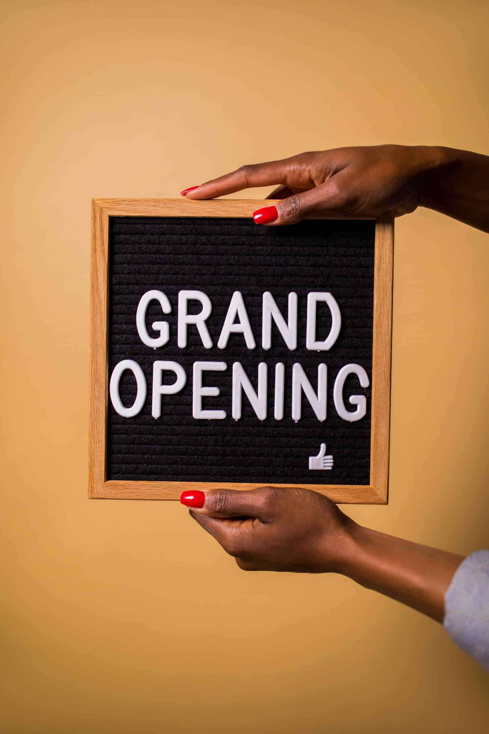 A grand opening sign held up outside a new retail store, marking a store launch day
