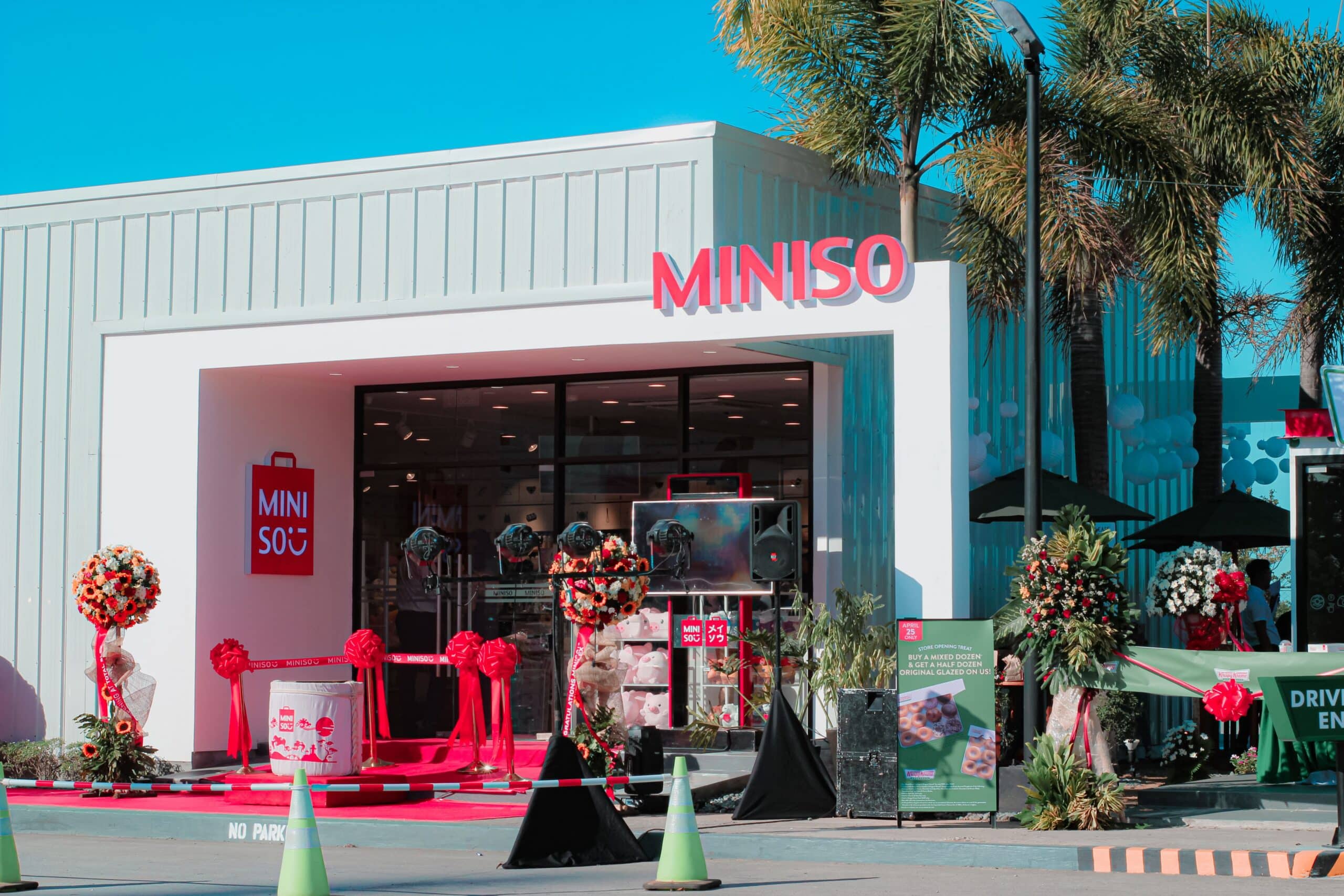 A retail store entrance decorated for its grand opening day, with signage and balloons welcoming customers