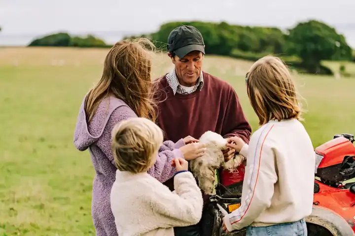 A family meeting a farmer and his lambs on a Feather Down working farm