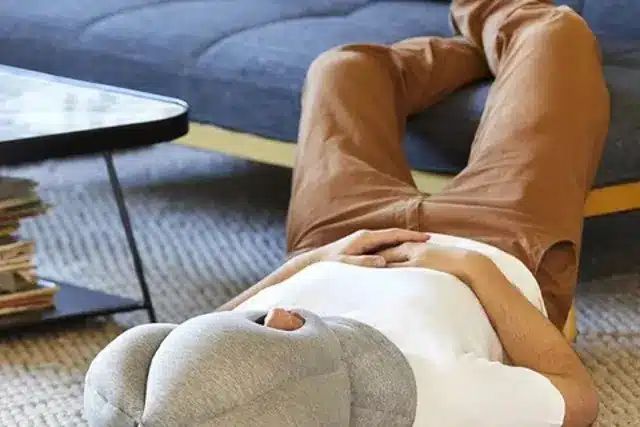 A person resting with an Ostrichpillow travel pillow